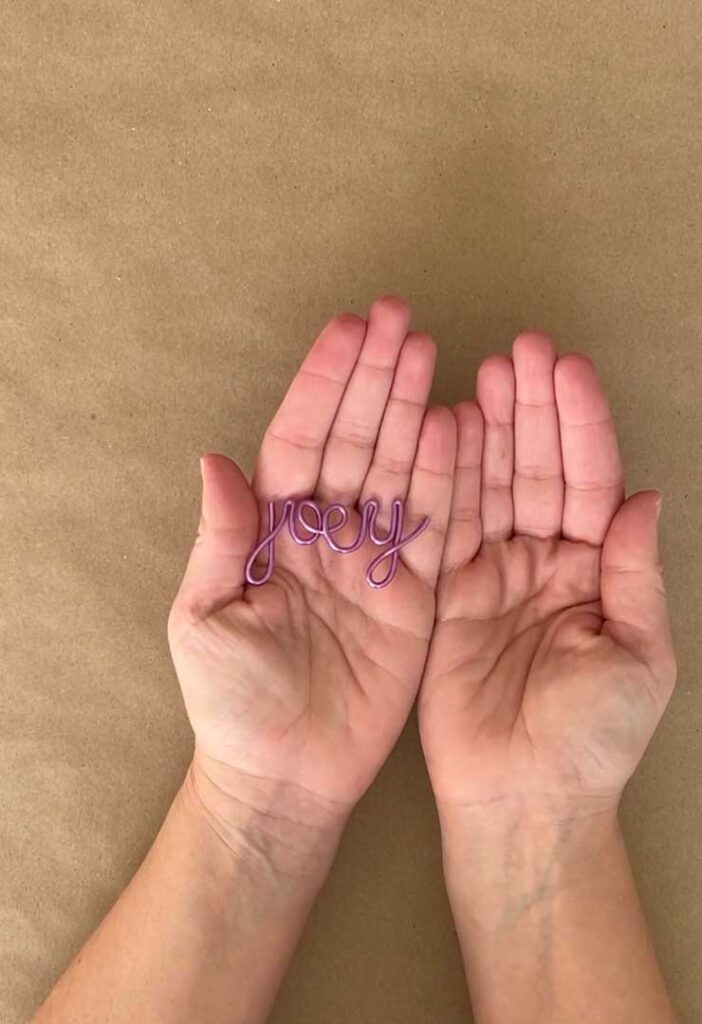 hand holding purple metallic wire name Joey