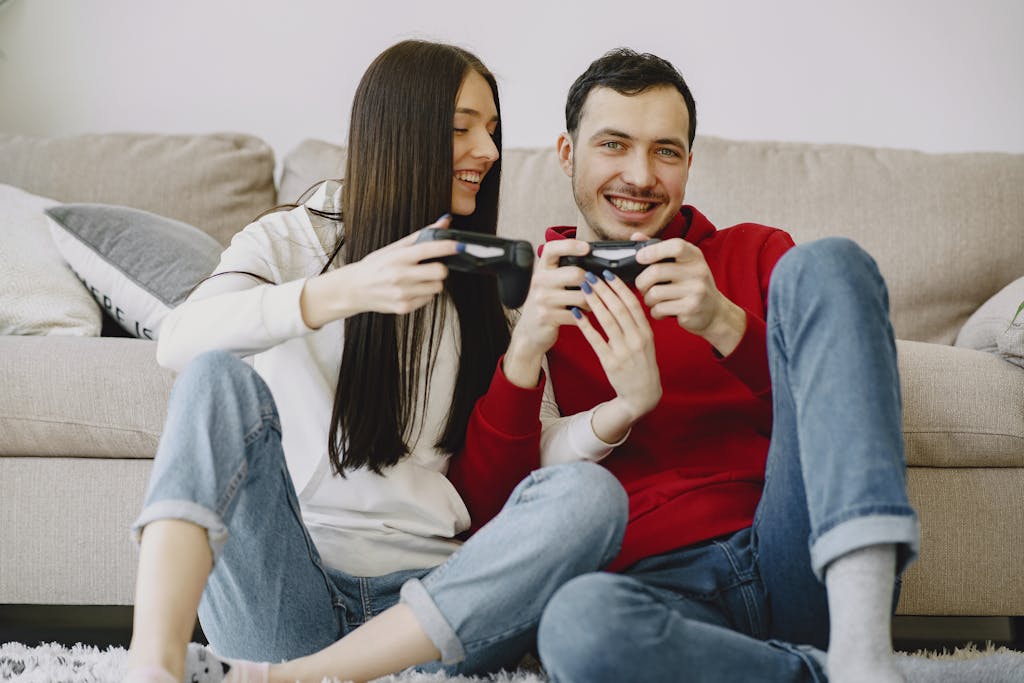 Happy couple sitting on carpet while playing videogame